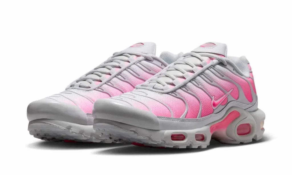 Angled view of the Nike Air Max Plus pair emphasizing the flowing TPU cage, visible Air units, and pink-to-white gradient upper