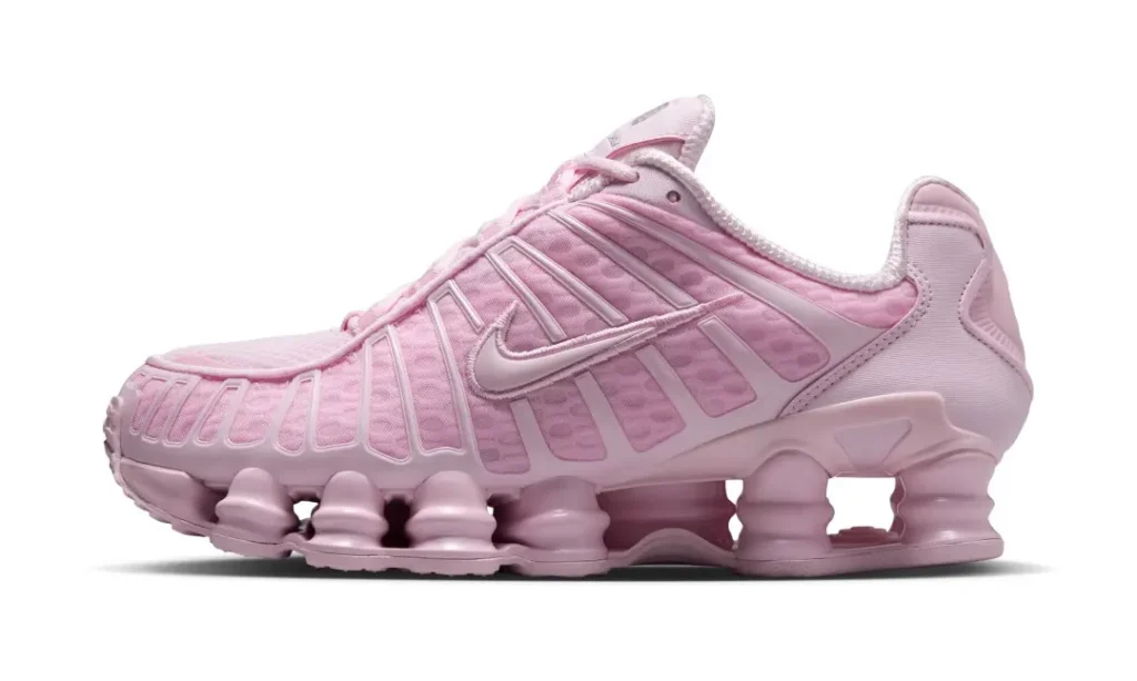 Soft pink Nike Shox TL shown in profile against a white background, featuring breathable mesh, molded TPU cage overlays, tonal Swoosh branding, and full-length Shox column cushion