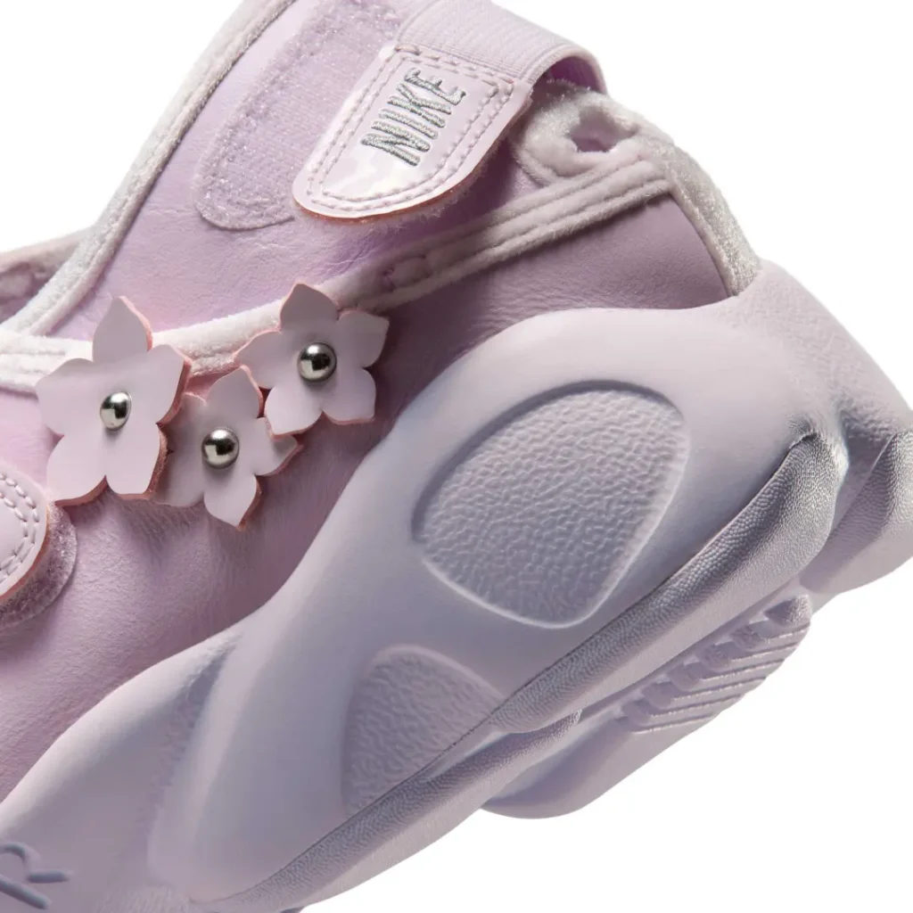 Close-up of the Air Rift upper featuring the hook-and-loop strap, soft suede trim, floral appliqués with metallic bead centers, and layered construction