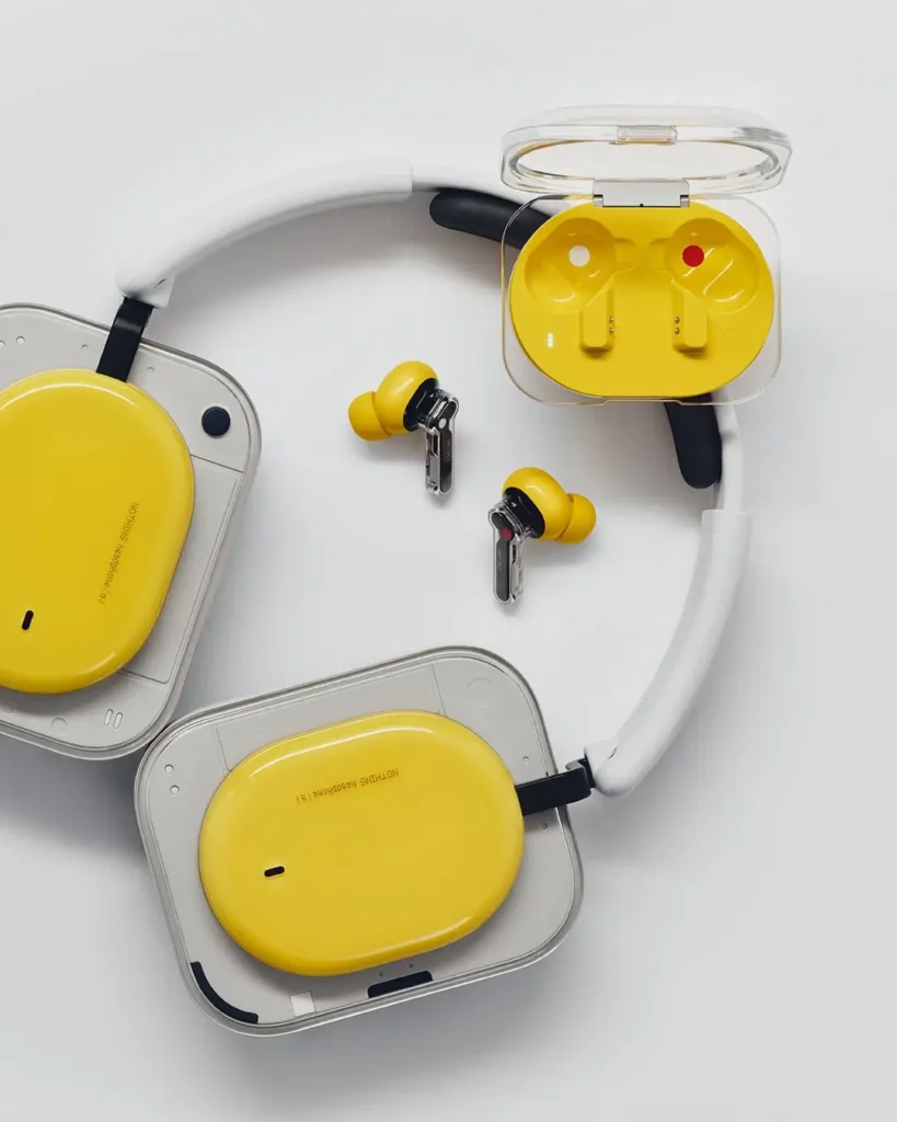 Yellow Nothing headphones, earbuds, and an open charging case are displayed together on a light gray surface, emphasizing the coordinated transparent industrial design across the product lineup