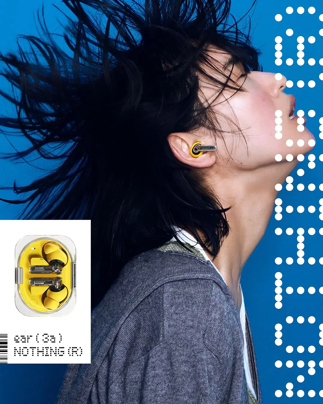 A model with windswept black hair wears the yellow Nothing Ear (3a) wireless earbud against a vivid blue background. The transparent stem and yellow silicone tip stand out, while an inset displays the matching earbuds inside their clear charging case.