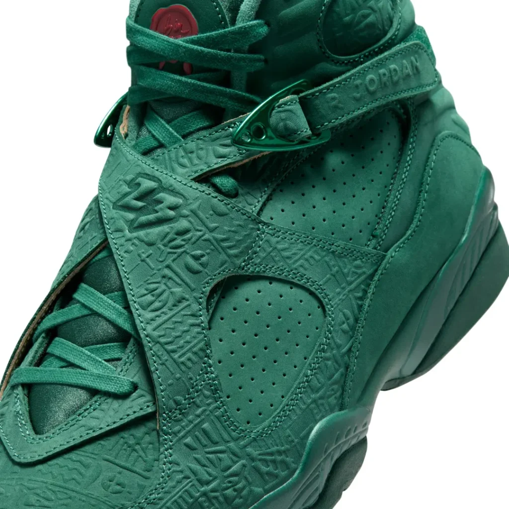 Close-up of the Air Jordan 8 x SoleFly crossover straps featuring embossed geometric artwork, metallic green hardware, perforated leather panels, and tonal "Air Jordan" bran