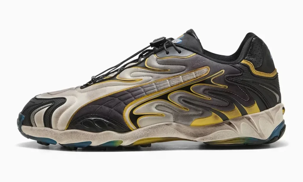 A lateral side profile of the sneaker showcases its sweeping flame inspired overlays, metallic silver upper, quilted midfoot panel, yellow detailing, sculpted CELL midsole, and blue tinted outsole pod