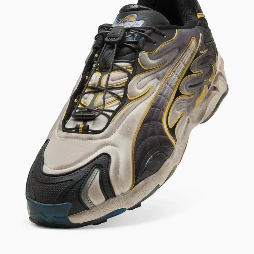 A detailed close up of the forefoot and lacing system shows the toggle speed lace closure, metallic silver textile upper, textured black toe guard, quilted side panel, and carefully applied vintage inspired finish