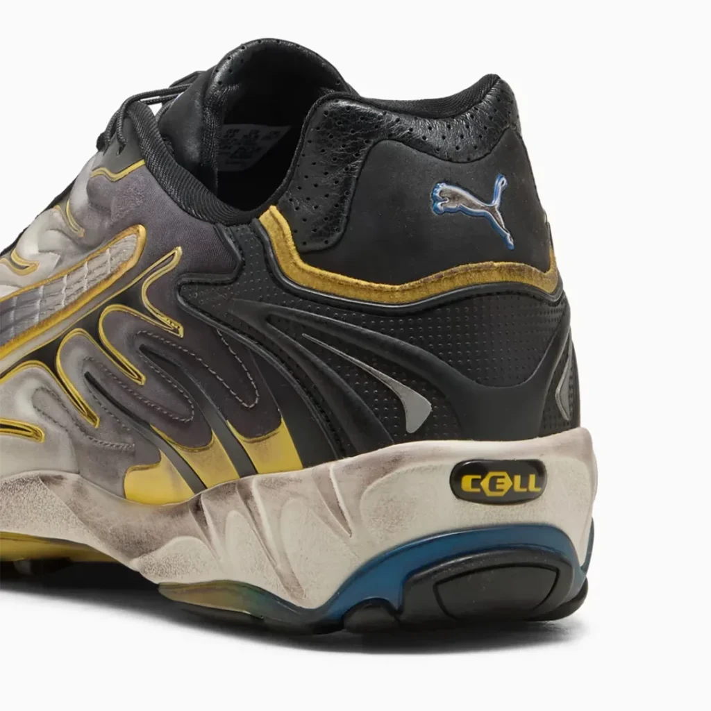 A close up of the heel highlights perforated black leather, embroidered PUMA cat branding in blue and silver, yellow trim, exposed CELL technology window, and the intentionally aged sculpted midsole