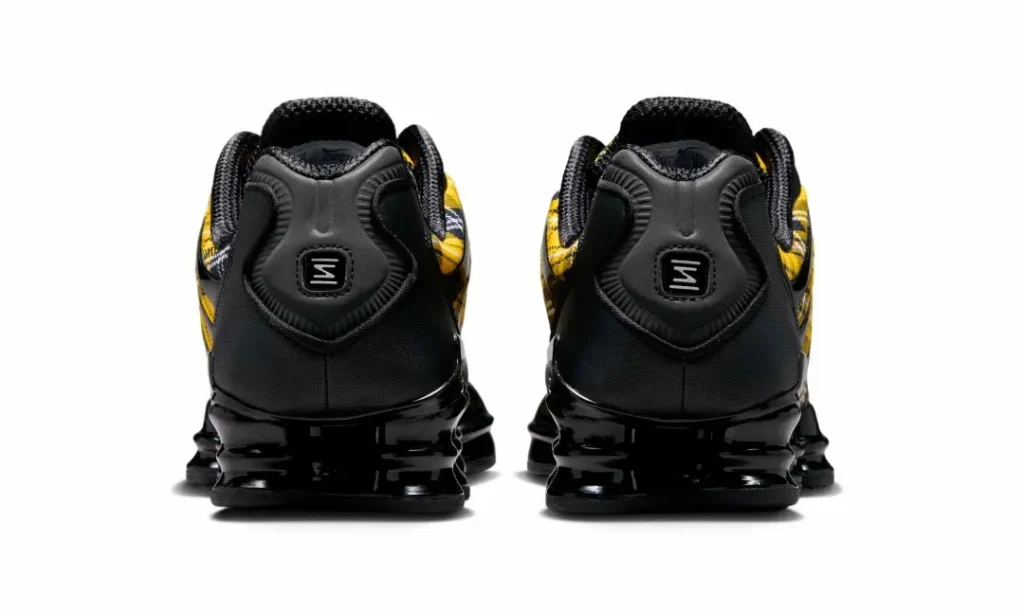 Rear view of the Nike Shox sneakers featuring black molded heel counters, padded collars, and glossy black Shox columns beneath the heel