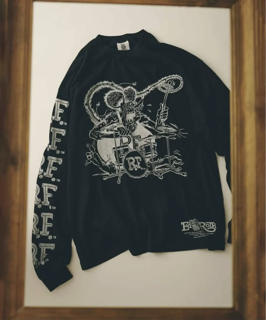 Black long sleeve Tee on display, screen printed with Ed "Big Daddy" Roth's Rat Fink character playing drums, repeating "R.F." lettering down the sleeve, and an "Ed Roth" logo lockup near the hem