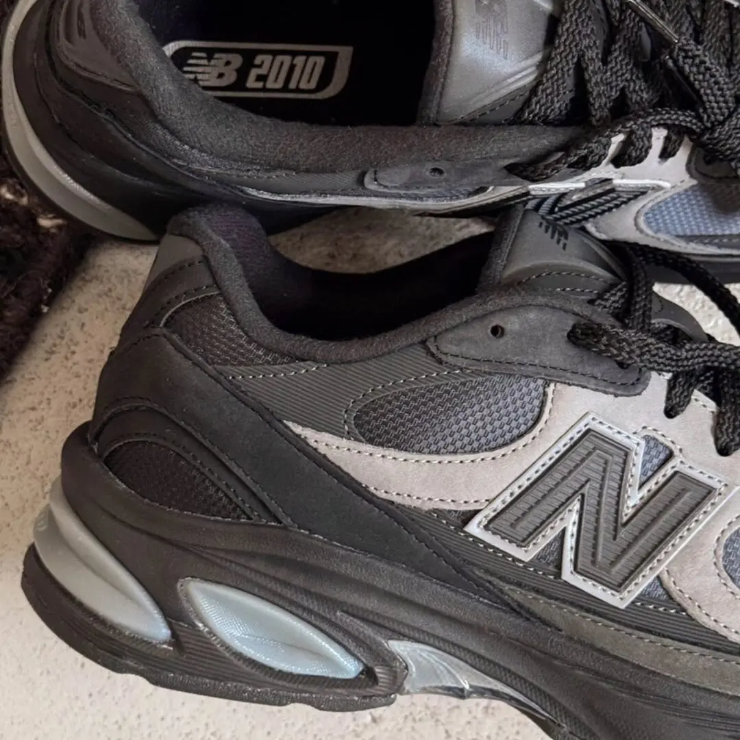 Close-up of the New Balance U2010 'Black/Harbor Grey' showcasing layered black suede, grey mesh panels, oversized N branding, and sculpted ABZORB cushioning.