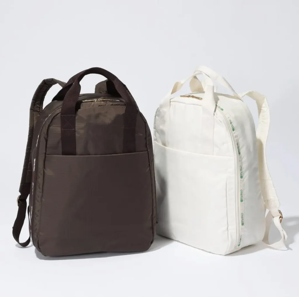 Brown and white LeSportsac backpacks shown side by side, highlighting clean silhouettes, front slip pockets, and lightweight travel-ready construction
