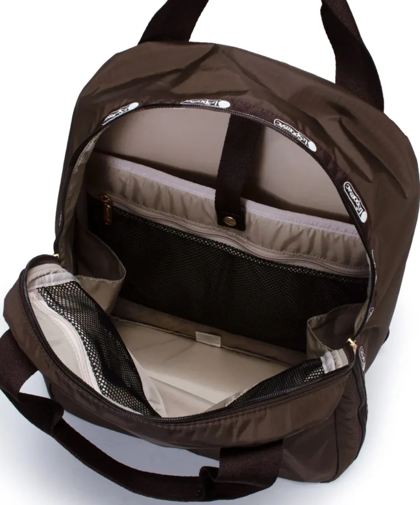 Interior view of a brown LeSportsac travel backpack featuring a padded laptop sleeve, mesh storage pocket, and spacious main compartment