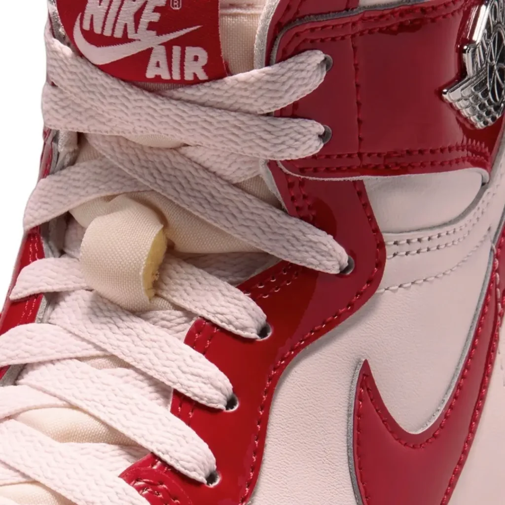 Close-up of the Air Jordan 1 High tongue and lacing system featuring a red Nike Air woven tongue label, white flat laces, exposed foam tongue, and glossy patent leather eyestay