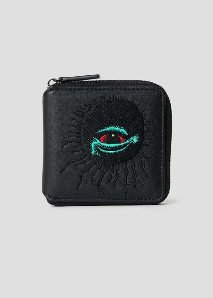 Black zip-around wallet with a large embroidered supernatural eye graphic in teal, red, and black surrounded by textured radial stitching