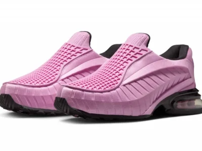 Pink slip-on Nike lifestyle shoe shown in an angled pair view, featuring a molded lattice forefoot overlay, sculpted satin-finish upper, black padded collar, and a glossy black full-length view Air unit