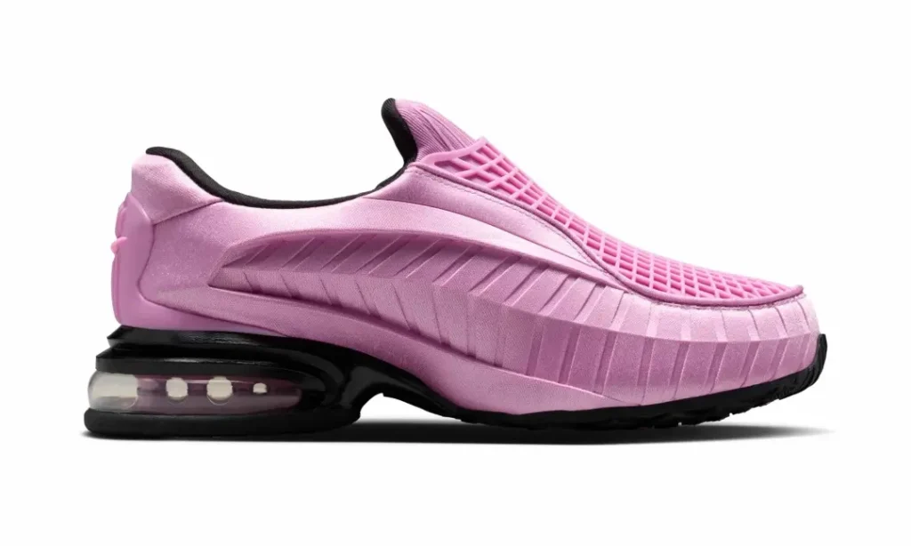 Medial side profile of the pastel pink Nike slip-on shoe highlighting the sculpted ribbed side panel, streamlined slip-on construction, and oversized black Air Max heel cushion