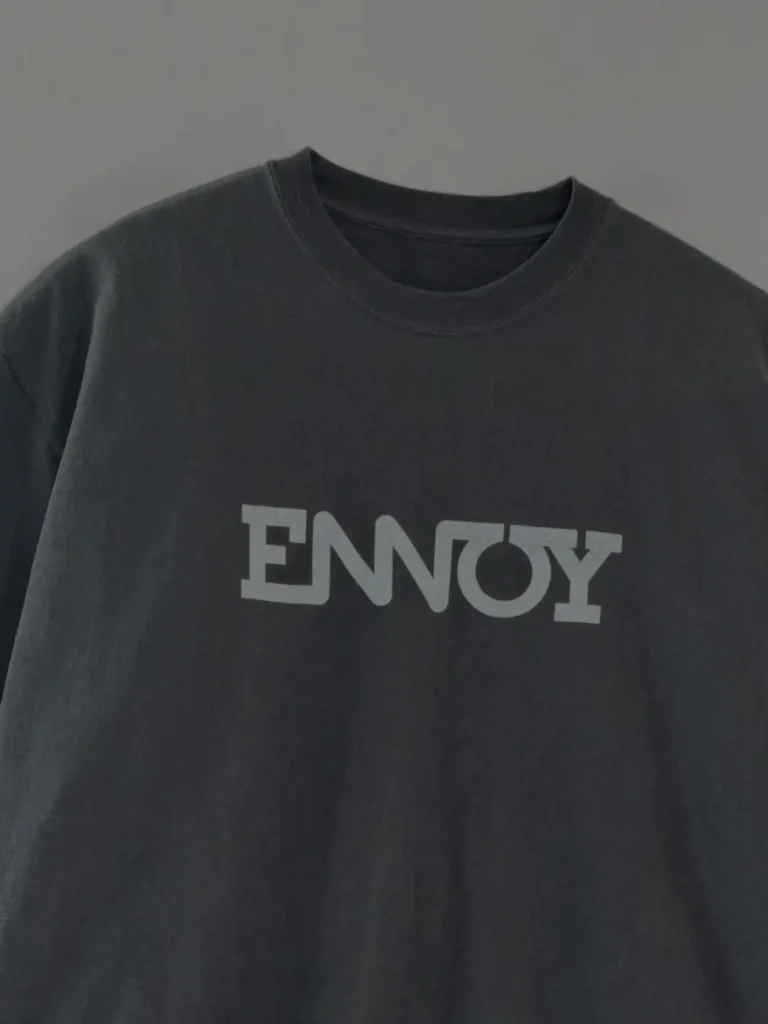 Close-up of a charcoal oversized ENNOY Tee with a bold tonal gray logo across the chest, showcasing the washed cotton finish and relaxed crewneck construction