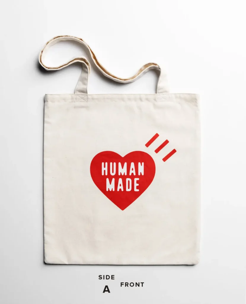 Cream canvas tote bag printed with the signature red Human Made heart logo and three accent marks on the front panel