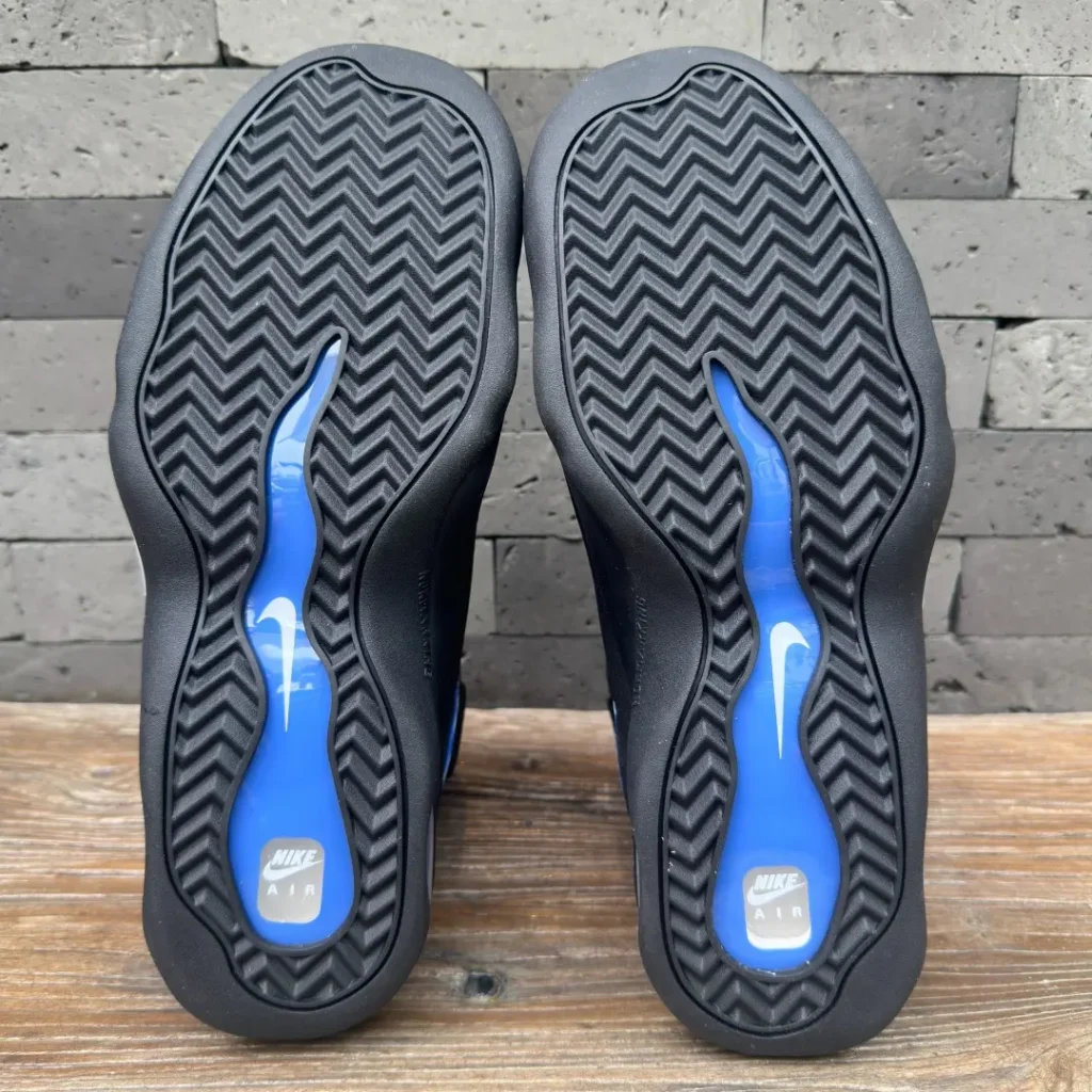 Outsole view of the Nike Air Bakin featuring a black herringbone traction pattern with a translucent royal blue midfoot shank and white Swoosh brand