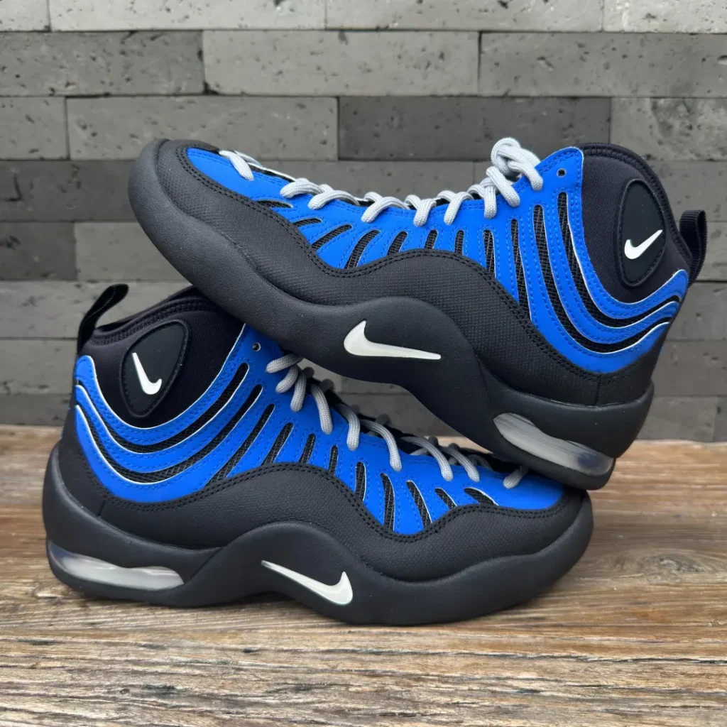 Nike Air Bakin basketball shoes in a black and royal blue colorway displayed in a stacked side-profile view, featuring synthetic paneling, wavy overlays, visible heel Air cushioning, and white Swoosh brand