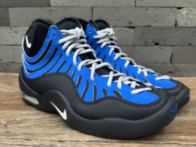 Three-quarter front view of the Nike Air Bakin showcasing the black and royal blue upper, light gray laces, rounded toe, and visible Air cushion