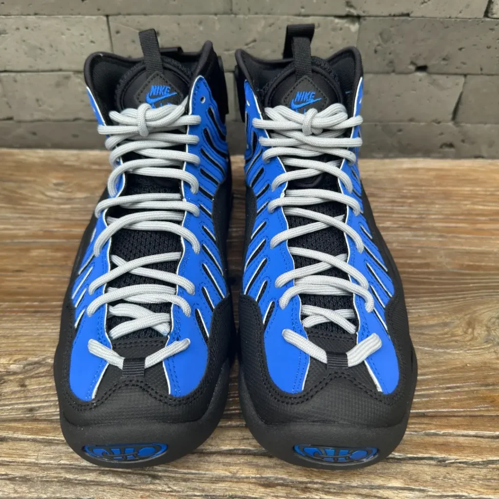 Front view of the Nike Air Bakin featuring light gray rope laces, black mesh tongue, royal blue overlays, and embroidered Nike branding on the tongue