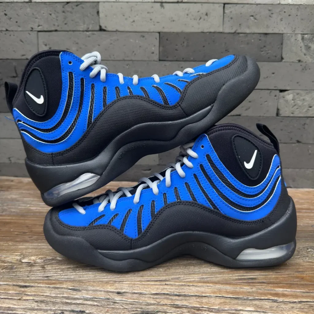Pair of Nike Air Bakin sneakers arranged in a stacked side view, emphasizing the black and royal blue tincture blocking, sculpted midsole, and visible heel Air cushion