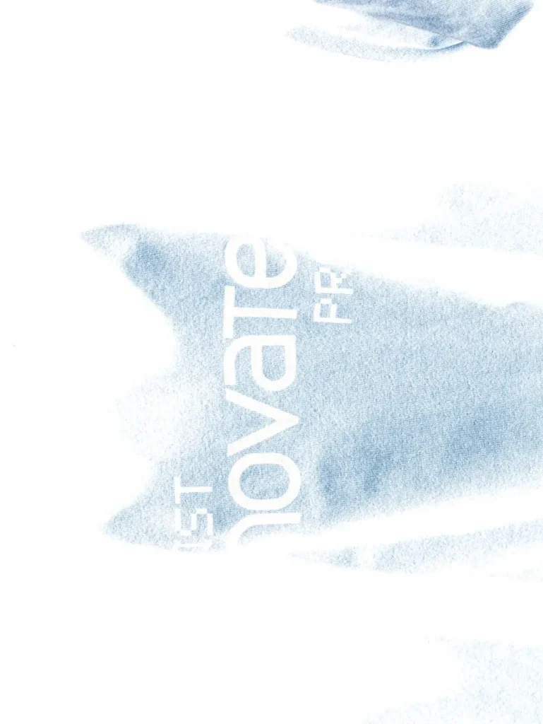 High-exposure close-up of white fabric with oversized cropped "innovaten PROOF" letter printed across the garment