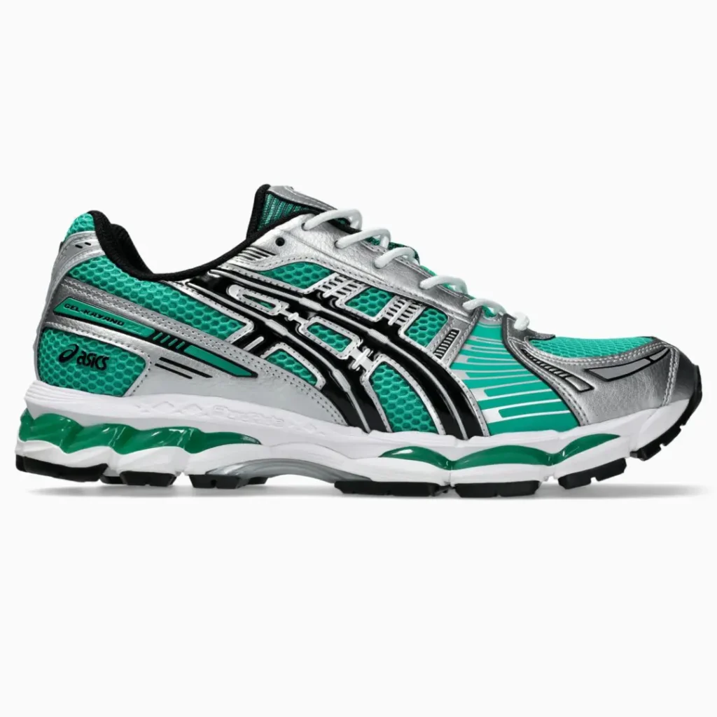 Side profile of the ASICS GEL-KAYANO 14 in a vibrant teal green colorway featuring breathable mesh underlays, metallic silver overlays, glossy black ASICS stripes, white laces, and a white midsole with green GEL cushion accent