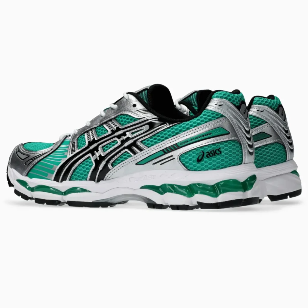Three-quarter rear view of the ASICS GEL-KAYANO 14 highlighting teal mesh panels, metallic silver heel overlays, black ASICS branding, visible GEL cushion, and a black rubber outsole