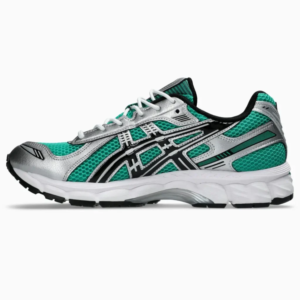 Medial side profile of the ASICS GEL-KAYANO 14 featuring teal mesh, metallic silver overlays, subtle black detailing, white laces, and a white midsole with translucent and green cushion element