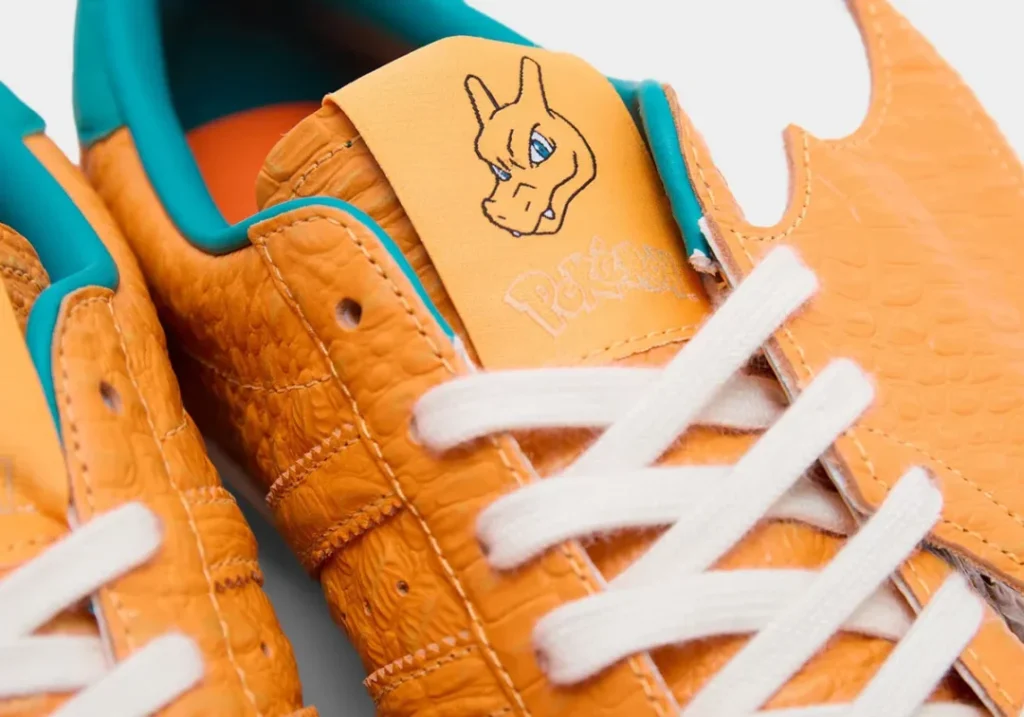 Detailed view of the Charizard-themed tongue label with embroidered Pokémon branding, orange textured leather, and white lace