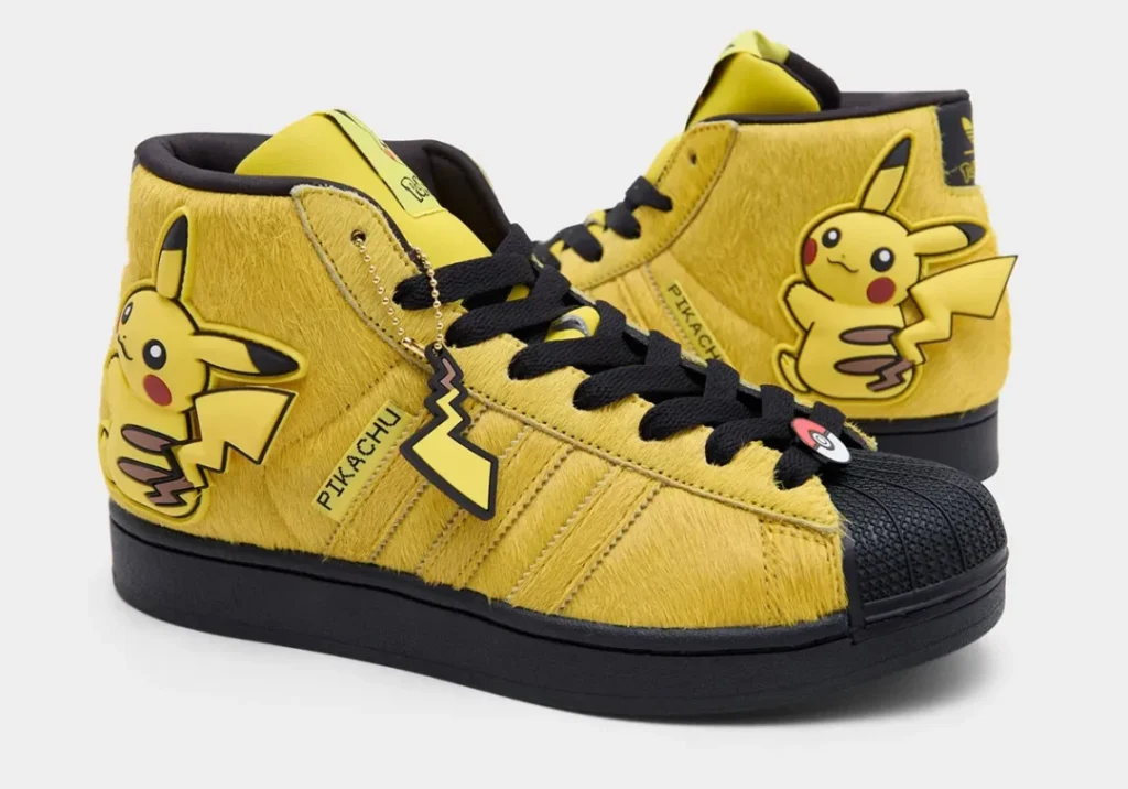 Pair of fuzzy yellow adidas Superstar Mid sneakers with Pikachu graphics, black shell toes, Pikachu lace charm, and Pokémon-themed detail