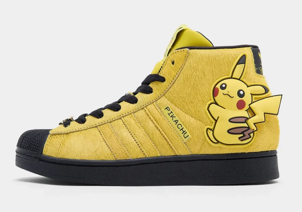 Side profile of the Pikachu-themed adidas Superstar Mid showcasing furry yellow uppers, embroidered "PIKACHU" branding, black sole, and oversized Pikachu graphic