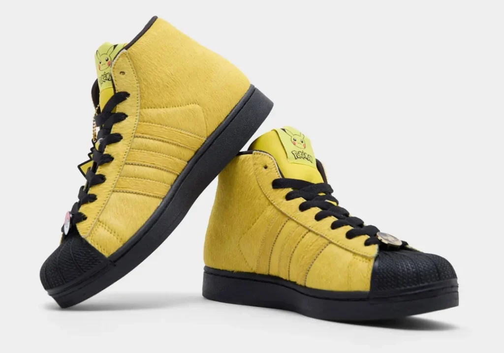 Angled view of the Pikachu Superstar Mid pair highlighting black laces, textured shell toes, furry uppers, and Pokémon lace accessor