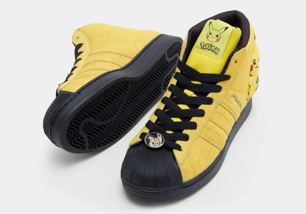 Pair of Pikachu-themed adidas Superstar Mid shoe showing the herringbone outsole, black shell toe, Pokémon tongue branding, and lace badge