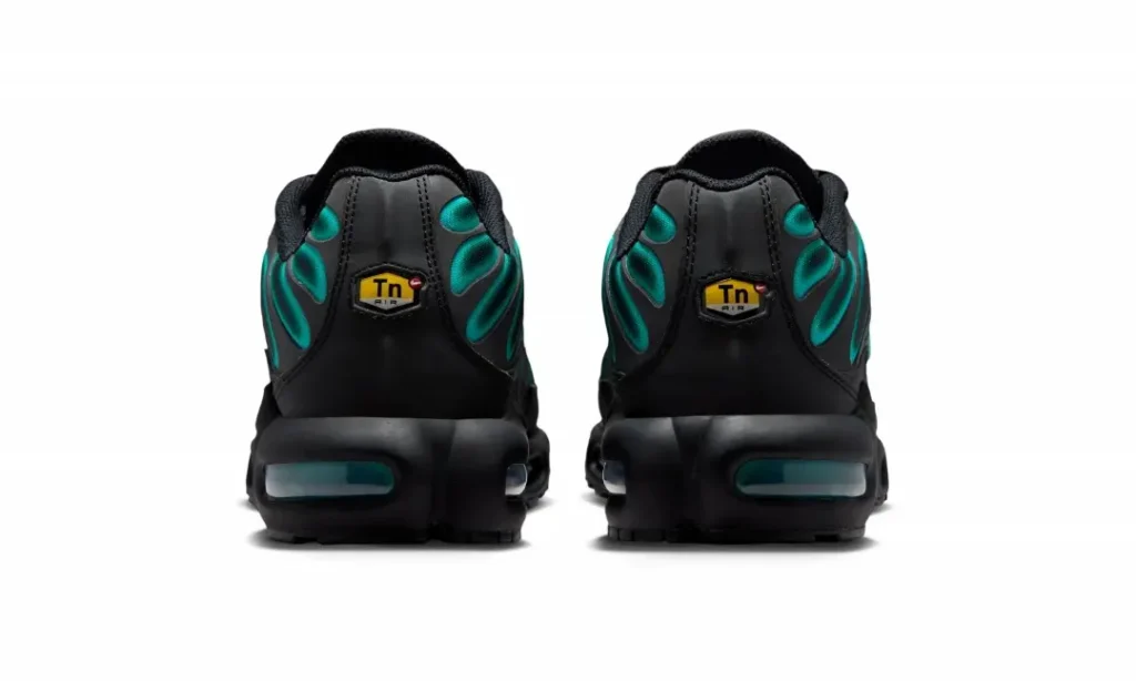 The back of the Nike Air Max Plus features black leather heel panels with yellow Tuned Air badges, teal overlay details wrapping the collar, and visible teal-tinted Air Max heel units integrated into the black midsole