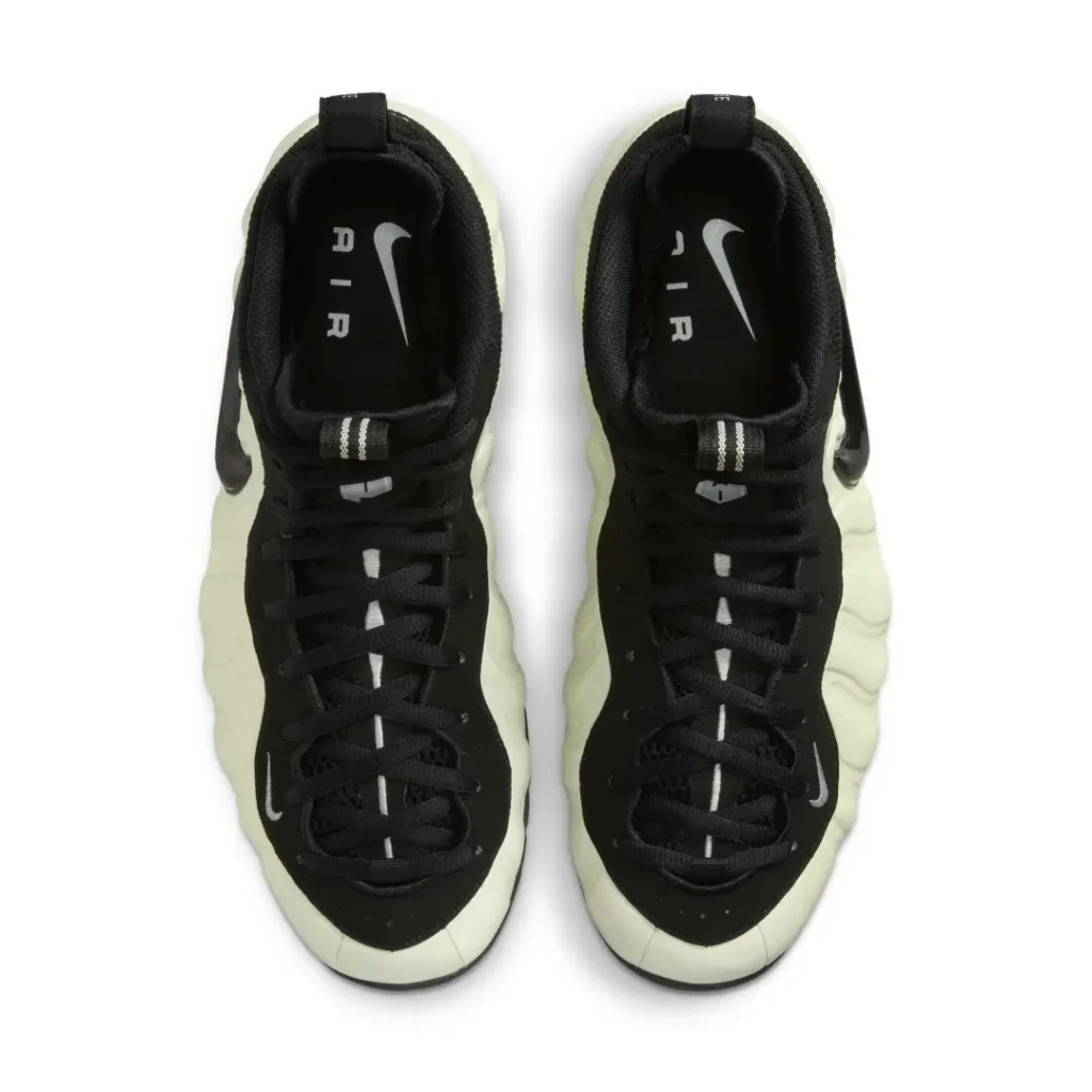 Top-down view of a pair of Nike Air Foamposite sneakers showing the black laces, insoles with "AIR" branding, and the full upper structure in black and cream tone