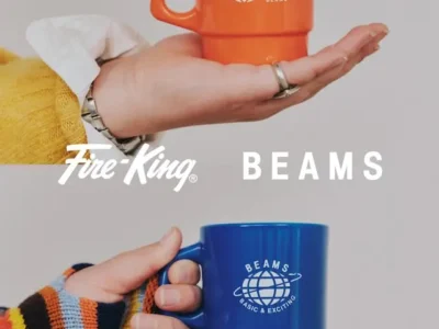 Promotional collage featuring BEAMS × Fire-King 50th anniversary stackable mugs. An orange mug rests on an open hand while a blue mug is held in a striped knit sleeve, both showcasing exclusive anniversary graphics against a clean studio background