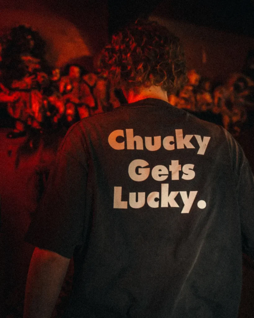 Back view of the faded black horror Tee featuring oversized white "Chucky Gets Lucky." typography across the upper back
