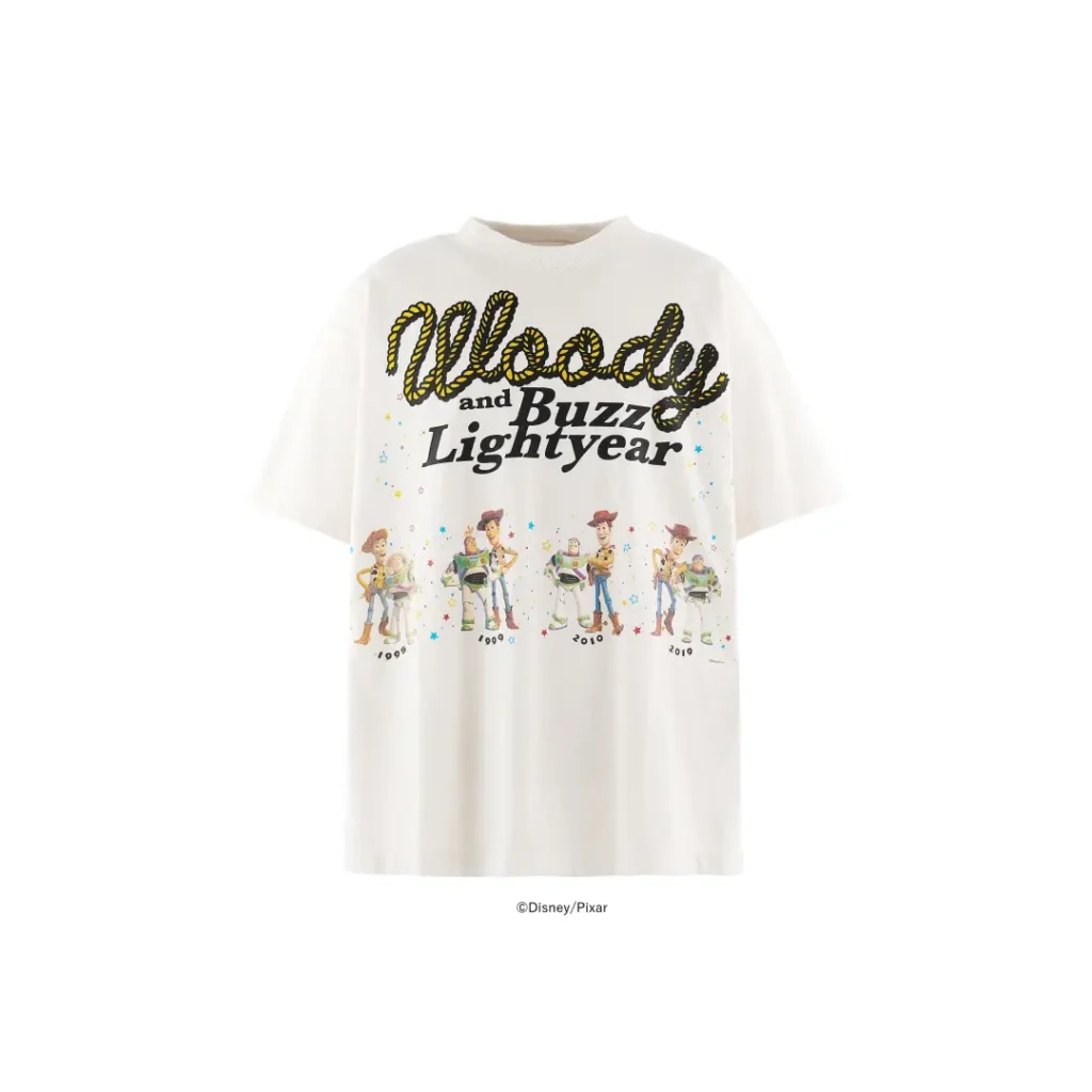 Front product image of a white oversized Tee featuring a colorful "Woody and Buzz Lightyear" graphic with character artwork spanning multiple Toy Story films and play confetti detail