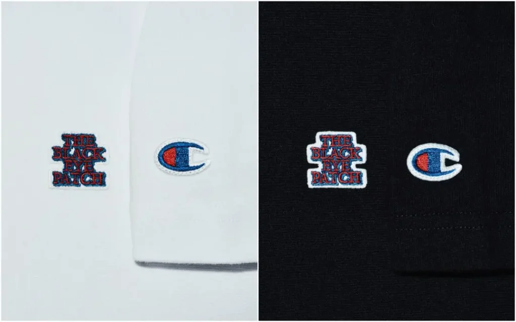 Side by side close up comparison of white and black Champion Tee showing embroidered The Black Eye Patch chest logo and Champion C logo stitched on the sleeve