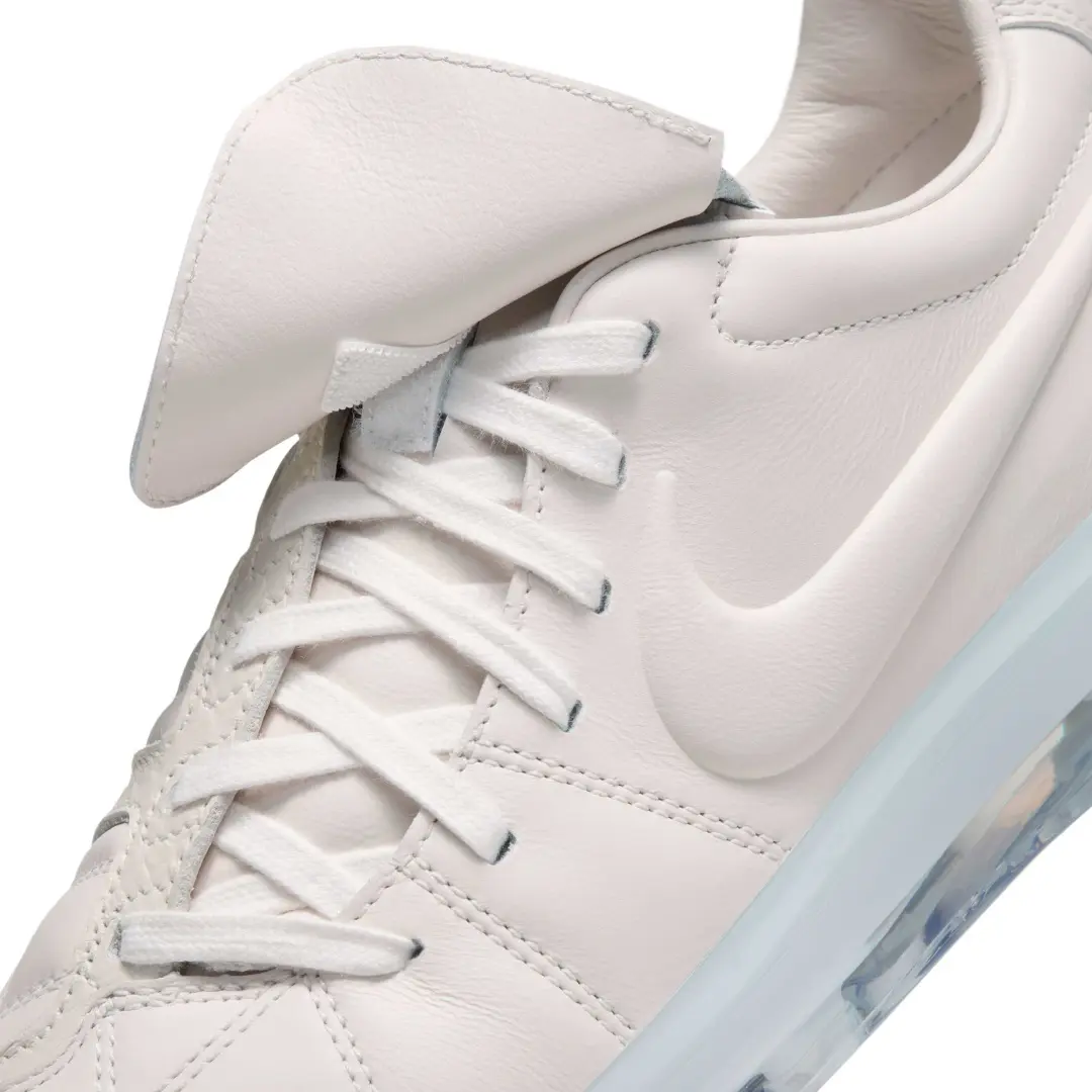 Close-up of the all-white Nike Total 90 showcasing its fold-over tongue, tonal Swoosh, white flat laces, premium leather upper, and translucent sole edge.