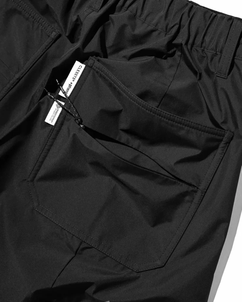 Close-up of the front pocket area showing belt loop placement, utility pocket construction, and accessory loop on the black pant