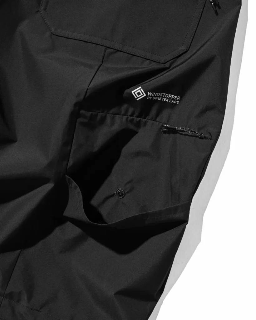 Detail of the oversized rear pocket with concealed zipper opening and woven collaboration tags on the black utility half pant