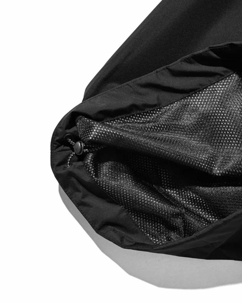 Interior view of the black pants' hem showing breathable mesh lining and adjustable drawcord system for customizable fit and vent