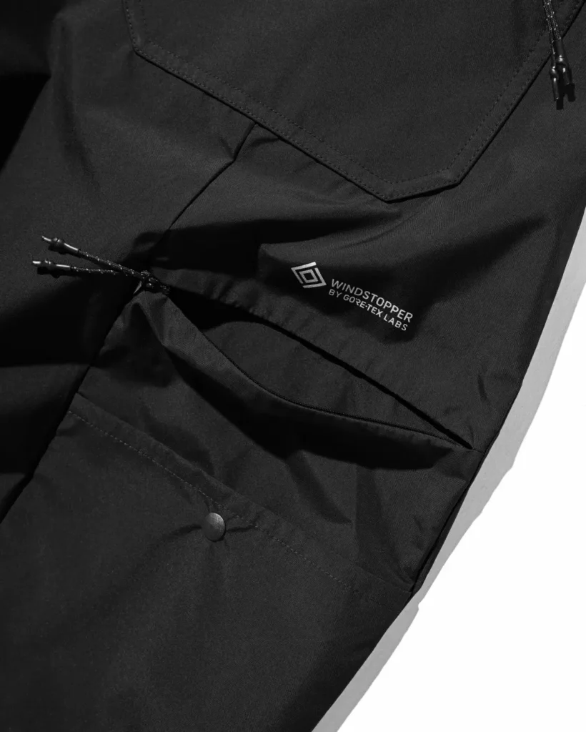 Close-up of the khaki pants' cargo pocket featuring WINDSTOPPER by GORE-TEX LABS branding, zipper detail, and oversized utility compartment