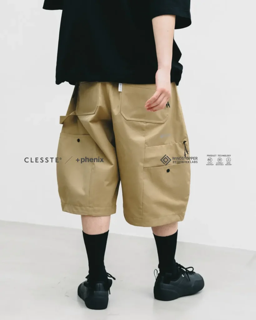 Rear close-up of khaki oversized technical balloon shorts highlighting oversized patch pockets, zip pockets, utility detailing, and structured volume paired with black socks and black shoe