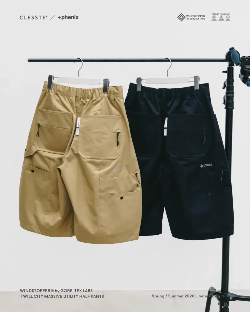 Black and khaki CLESSTE × +phenix utility half pants displayed side by side on a clothing rack, highlighting contrasting colorways and oversized balloon-inspired sil