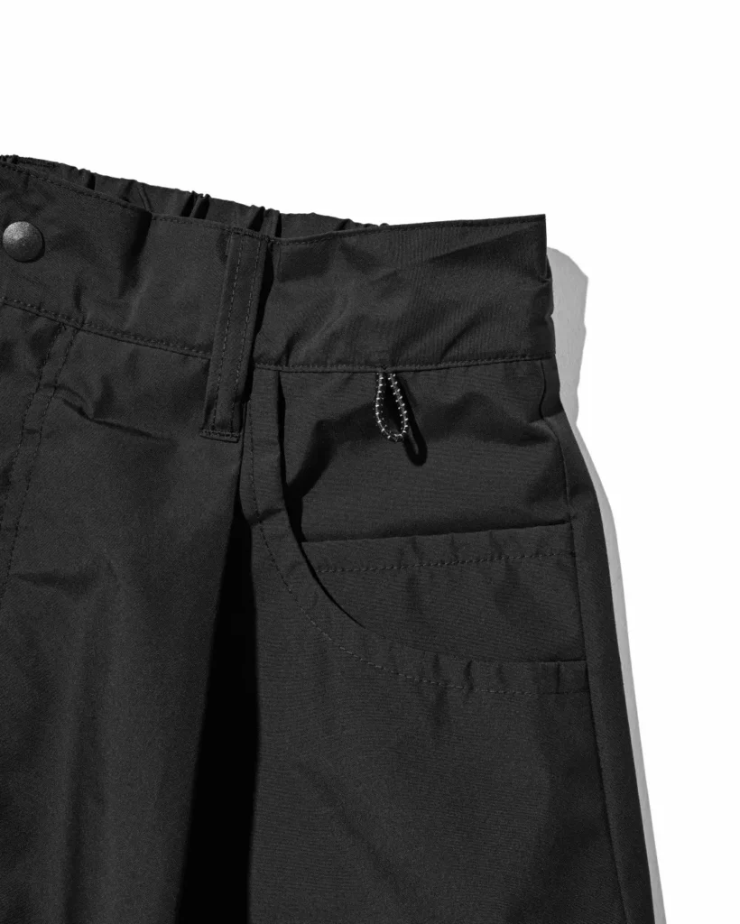 Full rear view of the black CLESSTE × +phenix utility half pants highlighting dual oversized back pockets, cargo compartments, and relaxed oversized fit