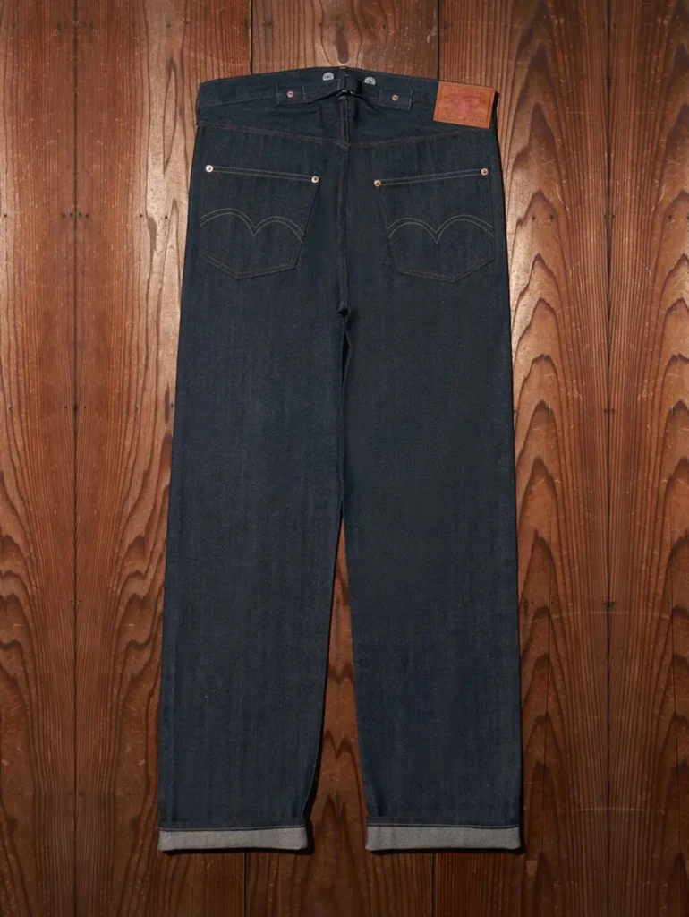 Rear view of dark indigo Levi's 501 XX selvedge jeans with signature arcuate stitching on the back pockets, leather Two Horse patch, and cuffed selvedge hem