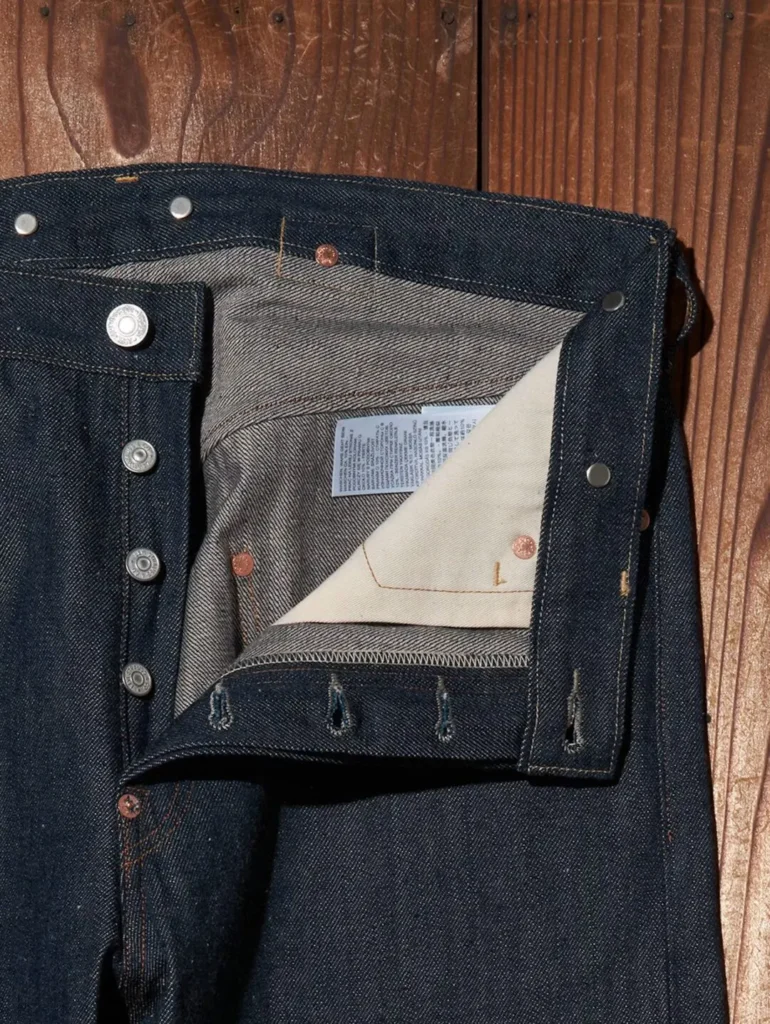 Close-up of the button-fly construction on Levi's 501 XX jeans showing silver-branded metal buttons, natural pocket bags, and heavyweight raw selvedge denim